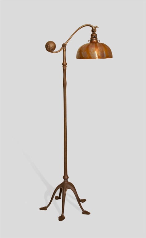 A Tiffany Studios bronze and favrile glass balance weight floor lamp comprising a five-footed gilded bronze base with an amber damascene cased blown glass shade decorated with silvery-blue iridescent feather design.