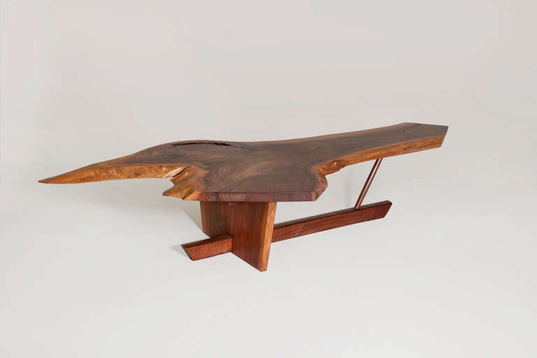 A spectacular large coffee table in walnut by master woodworker George Nakashima.  This sculptural live-edge table top features one of Nakashima's signature rosewood butterfly joints and rests on an architectural Minguren base.