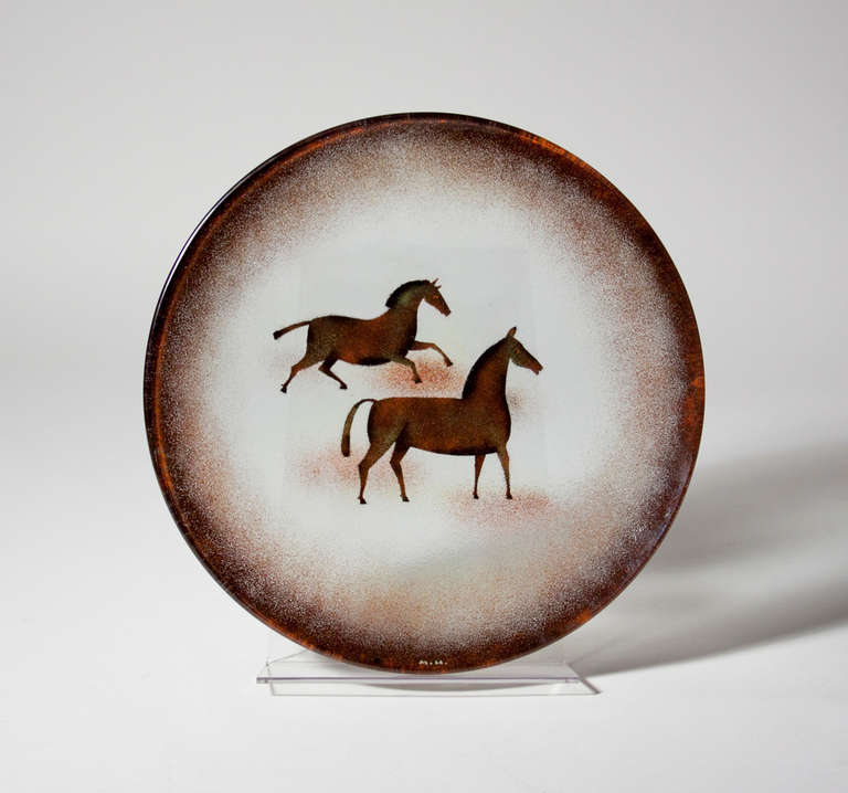 An enameled glass charger decorated with two horses by Modernist artist Maurice Heaton, signed.