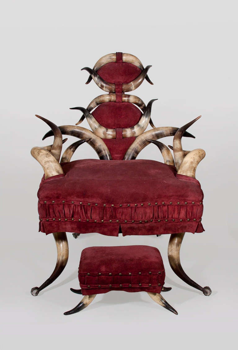 An exotic horn chair with matching ottoman dating from the late 19th century.  The chair, which is upholstered in a burgundy suede, rests on four pronged brass claw feet enclosing glass balls.

A similar example is in the collection of the Henry