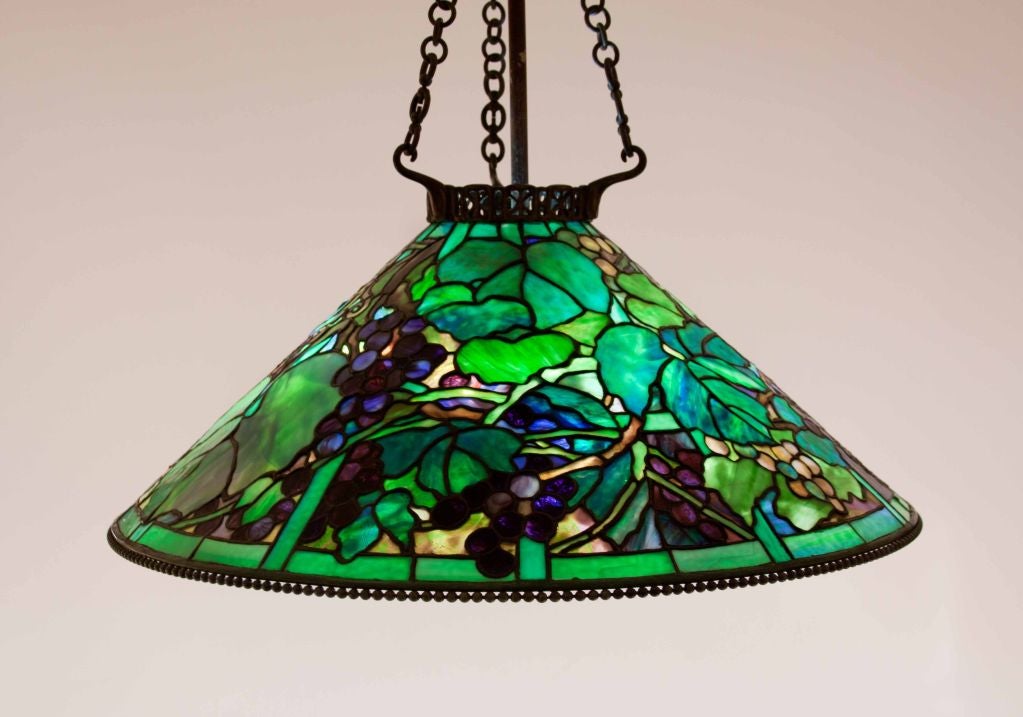 Rare and possibly special order Tiffany Studios Grape chandelier with vibrant green, blue, purple, lavender and burgundy glass, against a background in sunset colors; signed and with original bronze chain, rod, canopy and light cluster.