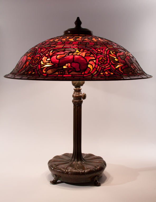 An exceptionally rare Tiffany Studios Salamander table lamp on a bronze decorated base.  The shade comprises deep red, purple, yellow and orange leaded glass, the base in a rich green brown patina, both signed.  Can also be sold on a decorated