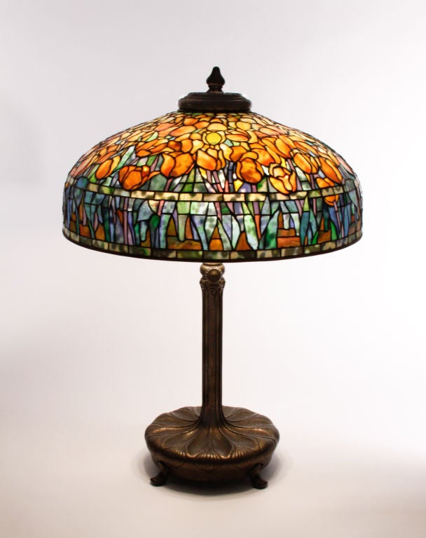 Tiffany Studios leaded glass and bronze tulip lamp on a decorated telescopic library base in an etched dore finish. The exceptional background glass compliments the brilliant orange tulips.  Both the shade and base are signed and the lamp has an