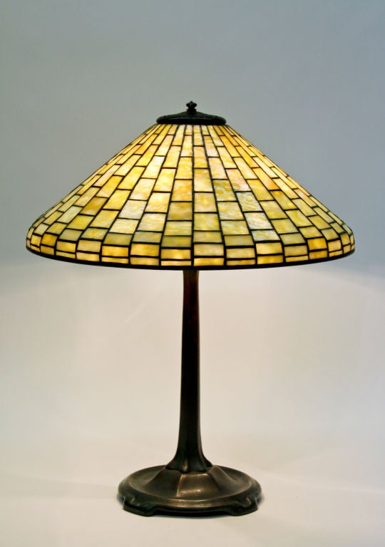 Tiffany Studios leaded glass and bronze table lamp comprising a cone-shaped geometric shade on a bronze 