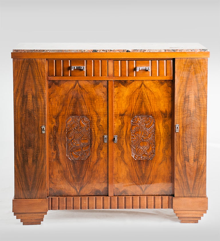 An Art Deco, book-matched walnut veneer with carved detailing and marble top