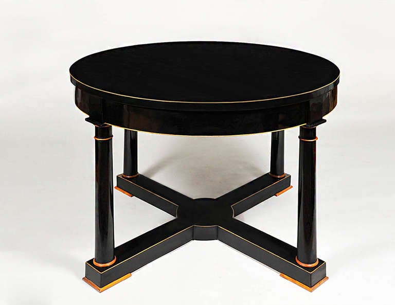 A Biedermeier center hall table with ebonized pear veneer with maple details, legs joined by ebonized cross members with highlights along edges in maple inlay.