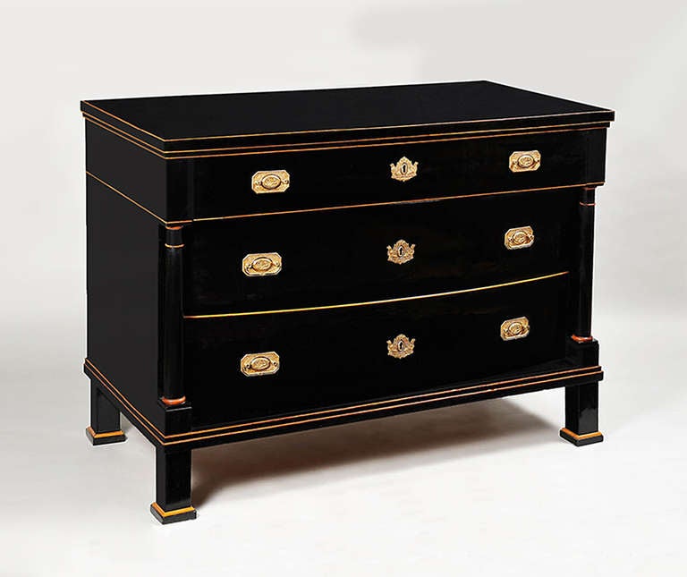 A three-drawer, ebonized Biedermeier commode. Ebonized wood with highlights in maple inlay, engaged Doric columns.