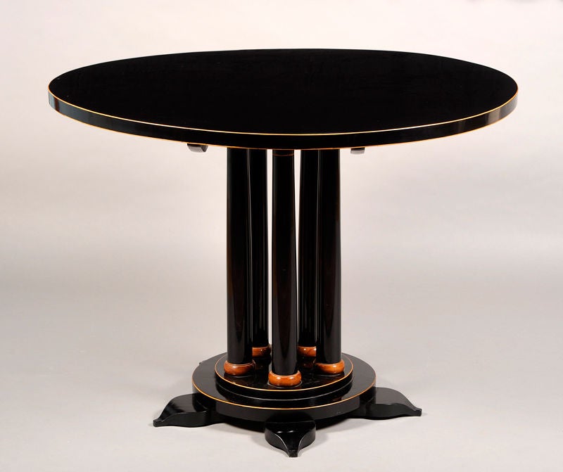 An elegant Biedermeier pedestal table in ebonized fruitwood veneer with maple detailing. Five Doric columns support table surface on tiered circular base.