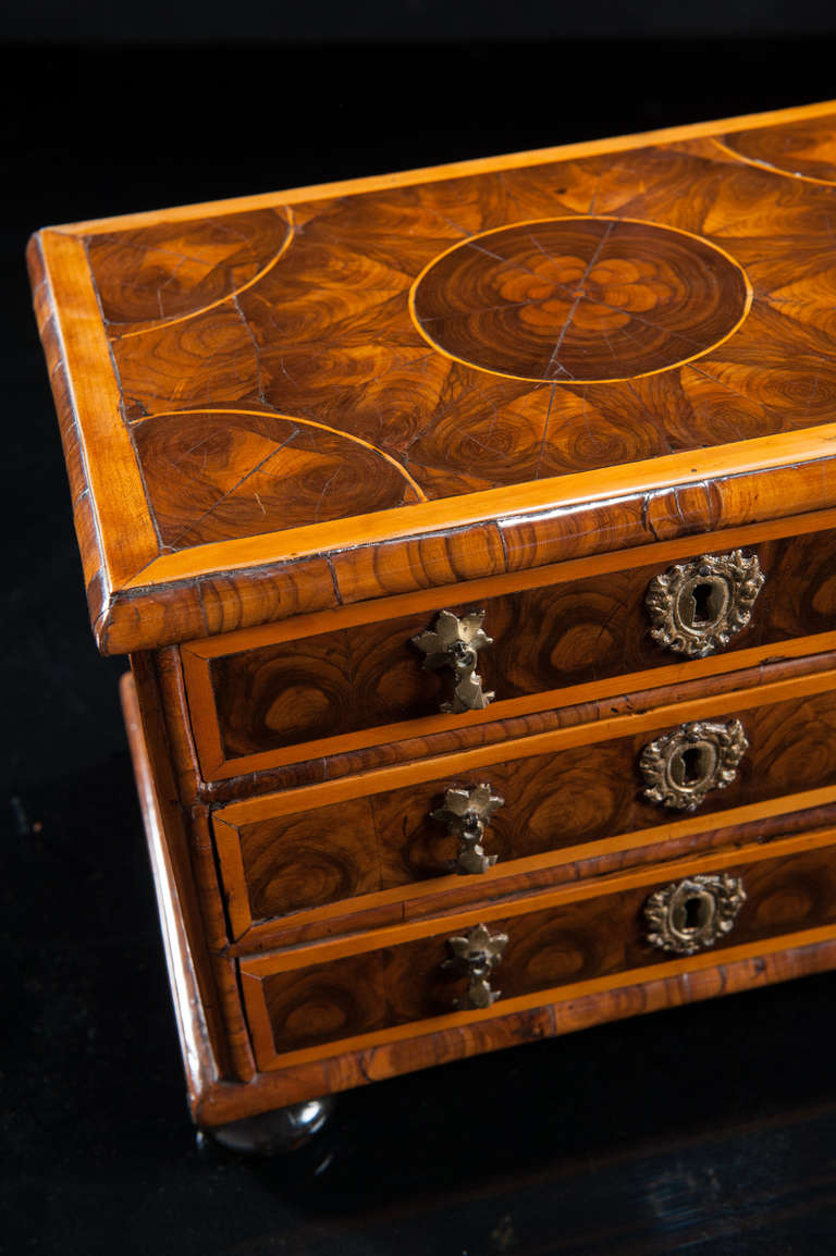 Very unusual William and Mary period miniature chest of applied oyster-wood veneer of English walnut. The top and the three graduated oak lined drawers cross-banded with fruitwood. 

Brasses and bun feet possibly original

English,
circa