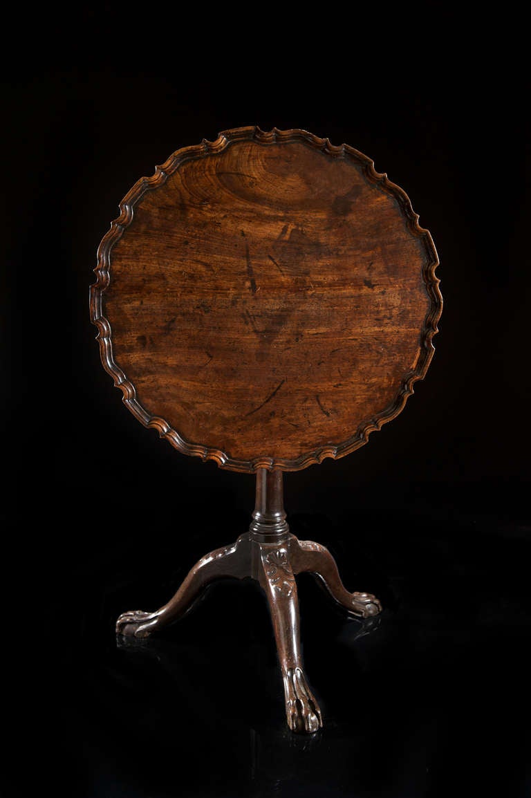 A mid-18th century Chippendale period carved mahogany piecrust tripod table. The circular top revolves on the bird cage support beneath and retains its original lock. The top, which pivots on the simple turned column base, still retains its original