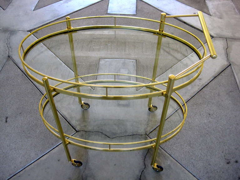A solid brass oval two tiered serving cart with glass shelves made by Maxwell-Phillips NY.  C. 1940's  The cart has been professionally polished with new glass
shelves.  The handle of the cart can be removed if desired.  The height in the listing