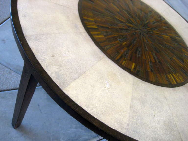 A circular cocktail table comprised of a wenge wood base that has been veneered with natural stingray skin (shagreen) and slices of tiger eye set in resin.
The table references the French Art Deco style of Jean Michel Frank.  Signed on the