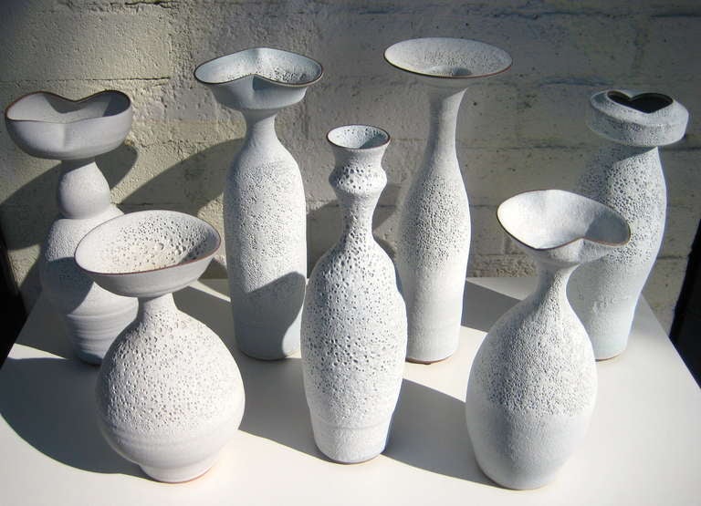 A group of seven hand thrown terra cotta vessels with a white 