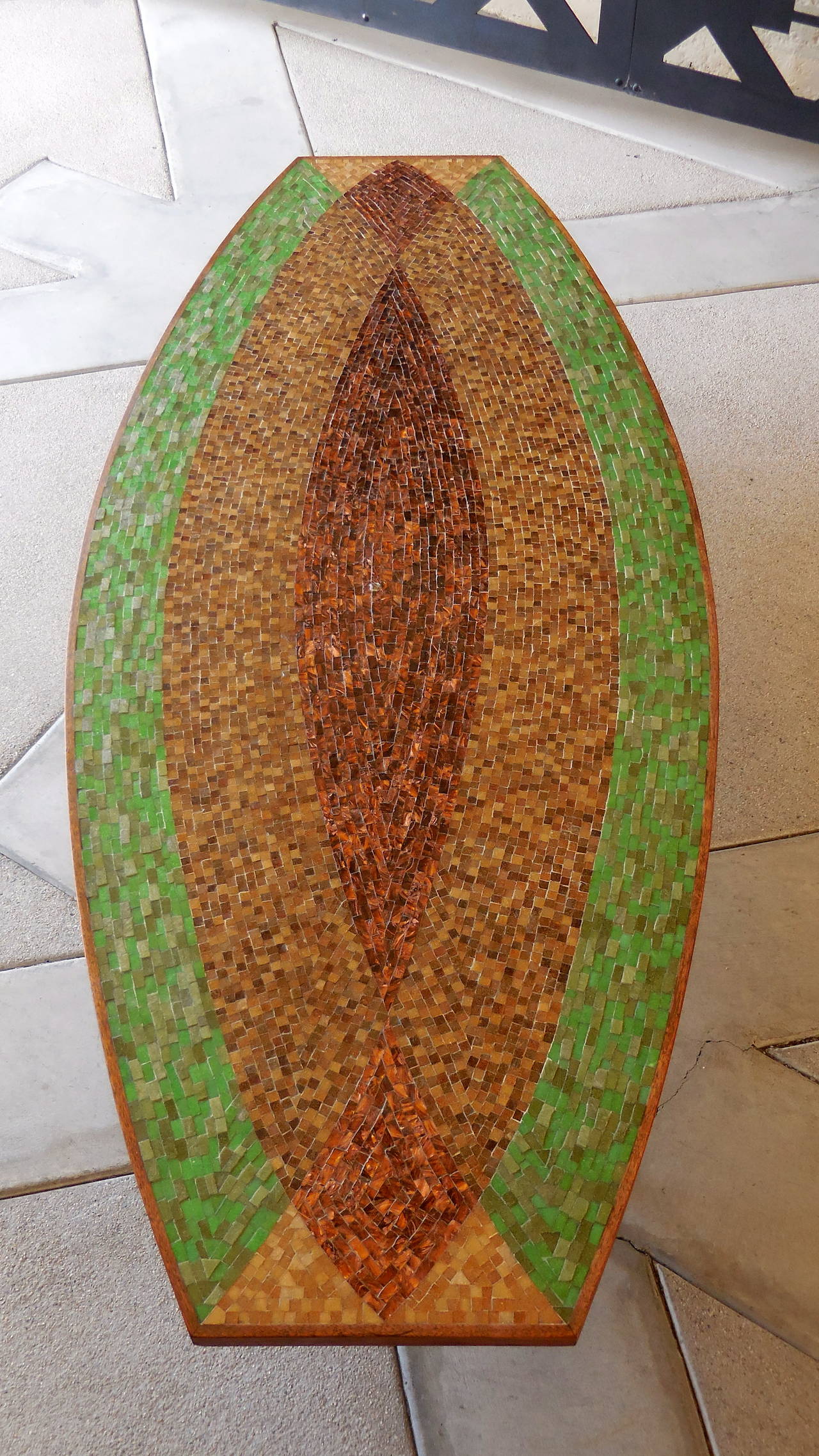 A large dynamic coffee table rendered in hand cut and laid glass mosaic tiles on a  walnut frame. This classic table from the 1950s is an excellent example of Mid-Century California design with the sly reference to the surfboard culture of the time