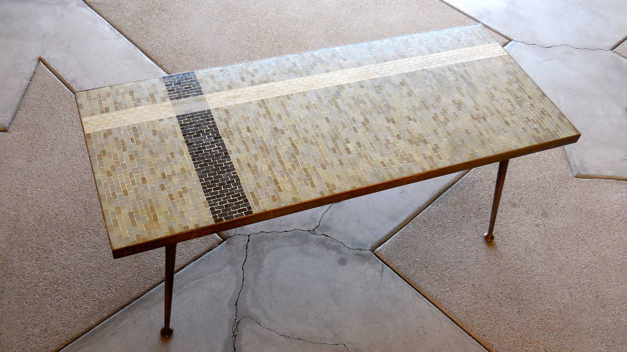 A handsome 1950s Italian coffee table. The top is all hand laid glass mosaic
tesserae set in a compelling striped geometric pattern. The frame and legs are solid patinated brass. The brass body with stiletto legs gives an element of glamour to the