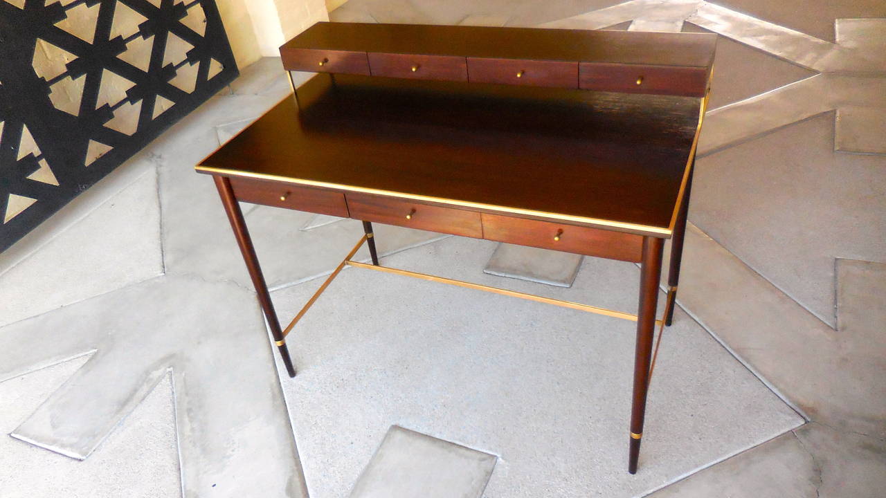 A superbly crafted walnut writing table with solid brass trim designed by Paul McCobb in the early 1950s and produced by H. Sacks and Sons of Brookline, Massachusetts. This particular desk from McCobb's highest end line, The Connoisseur collection,