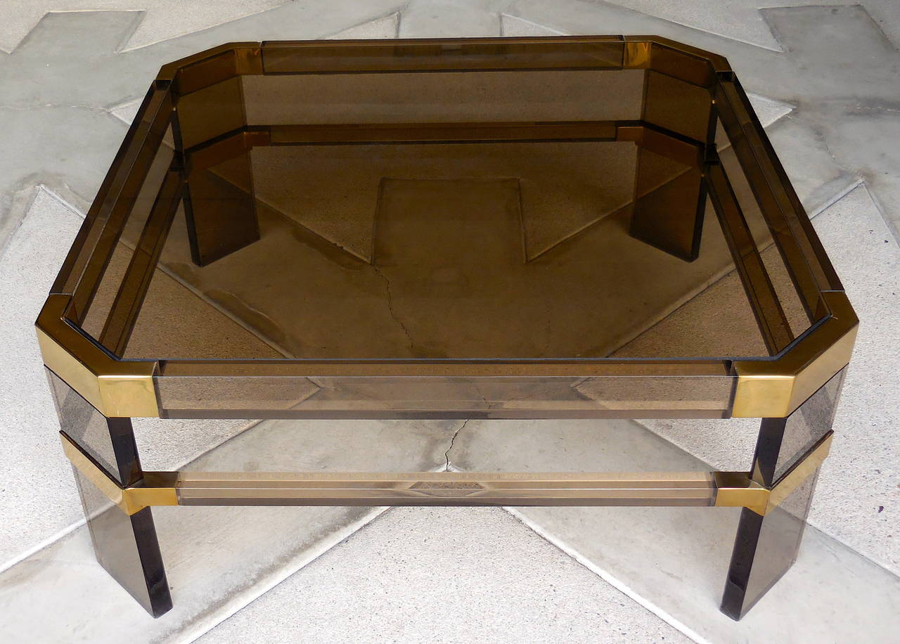 A sexy smoked Lucite and glass Metric Line coffee table with brass-plated metal mounts, made by Charles Hollis Jones in the 1970s. Items from the Metric Line were available through the Hudson-Rissman showroom and this piece, with smoked Lucite,