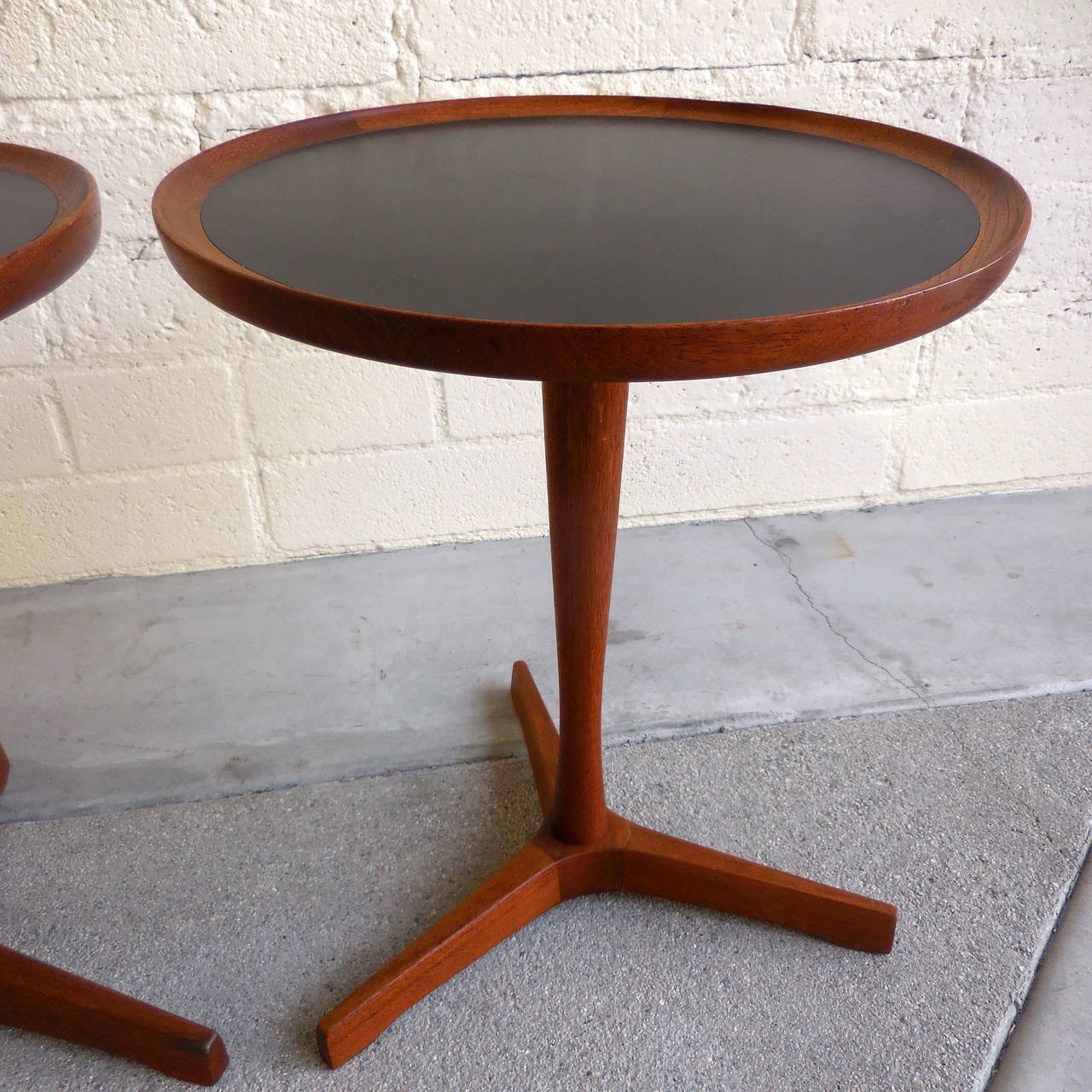 Beautifully constructed teak Danish side tables, circa 1955. These handsome little occasionals have the original black laminate tops for durability of use. Inscribed on the bottom and signed.
