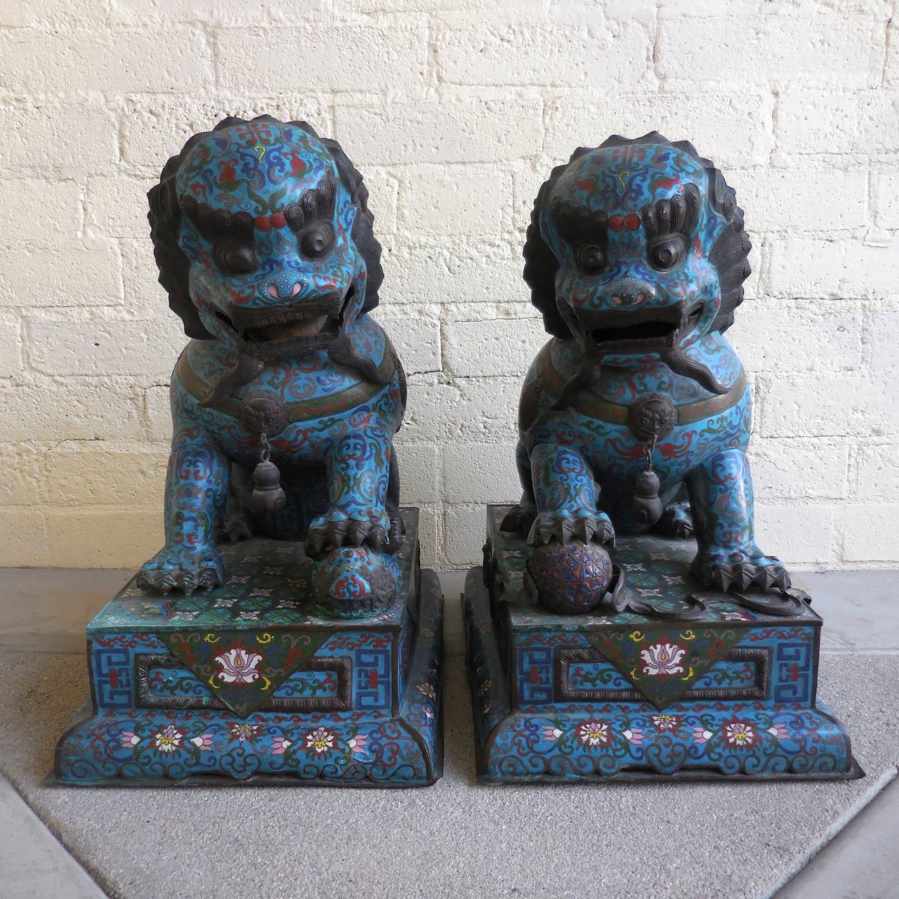 A stately pair of Chinese cloisonné Foo dog statues dating from the mid-19th century. This pair of statues is in very good original condition and the large-scale of this pair of statues puts them into the category of temple dogs. As customary with