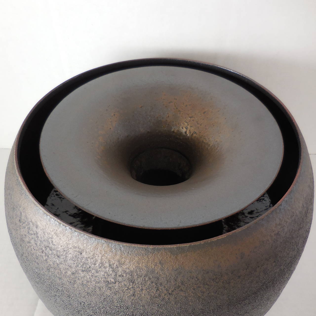 A truly spectacular, hand thrown double walled vessel by American artist Jeremy Briddell. This piece has a gunmetal or bronze glazed exterior with a luster glaze interior. The outer bowl is quite large being 16