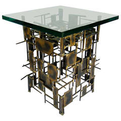 A brutalist sculptural side table with a thick glass top attributed to Marc Weinstein. C. 1970