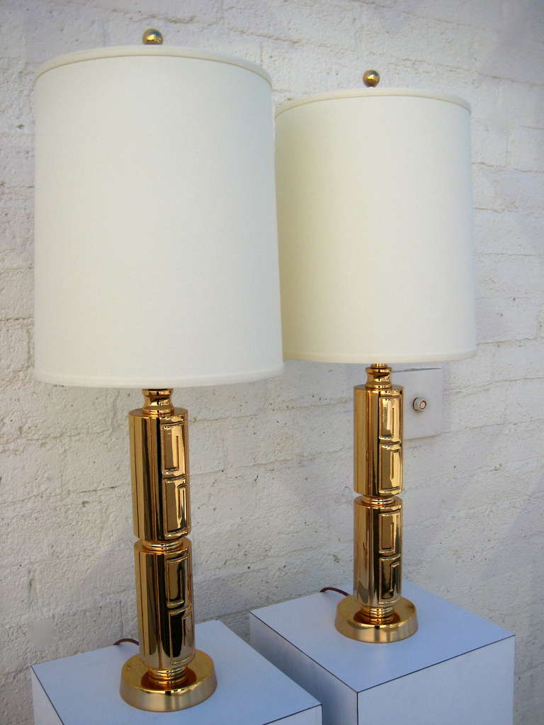 A chic pair of Neoclassical table lamps with greek key detailing attributed to Stiffel Lighting C. 1950's.   These lamps have been recently replated in a gold finish and retain all of the original parts, including the harps and finials.  They are