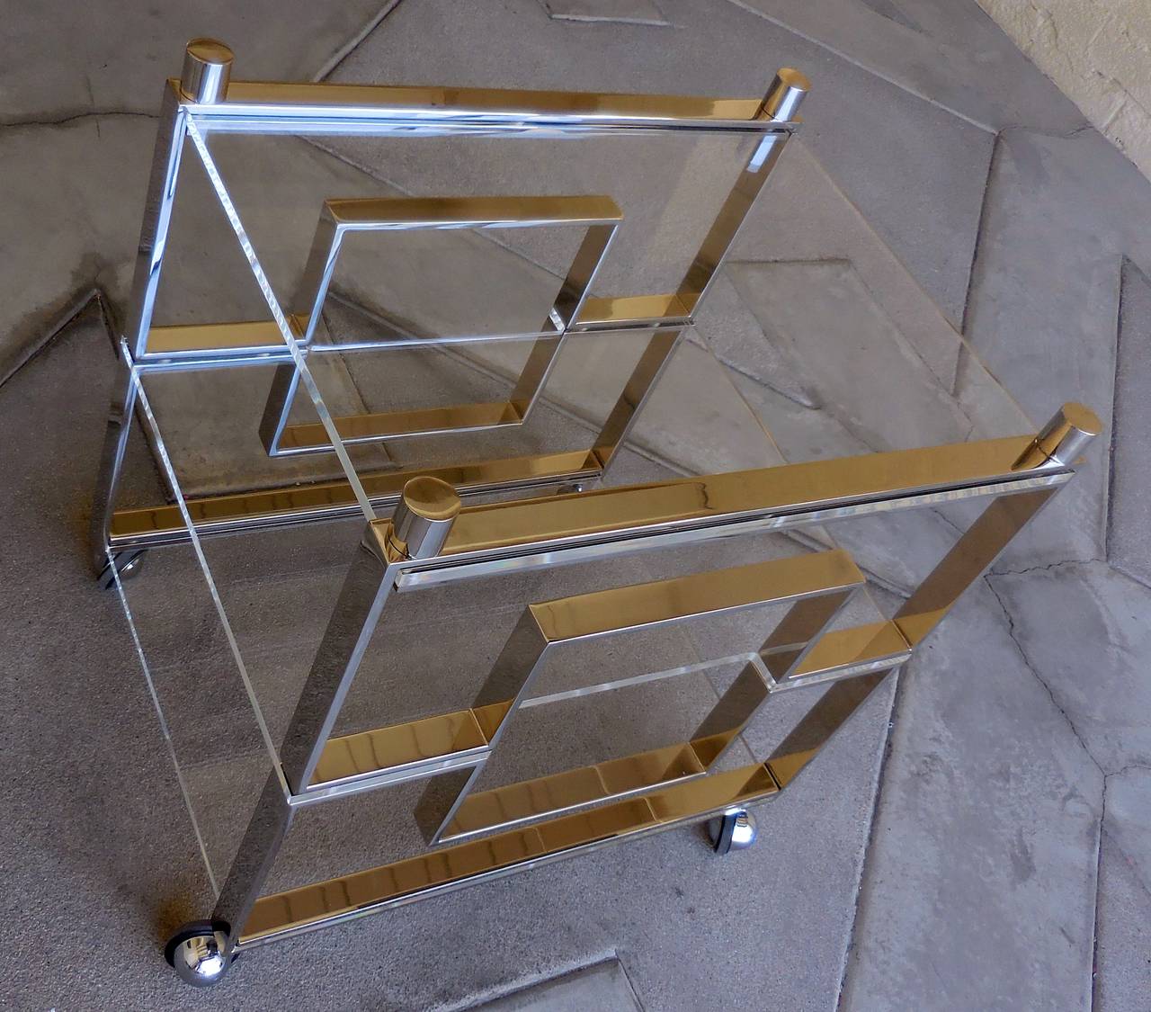 A nickel plated steel and Lucite serving or bar cart designed and created by Charles Hollis Jones.  The solid flat-bar steel on the cart has been plated in gleaming, polished nickel finish and each of the three shelves are Lucite.  This piece is