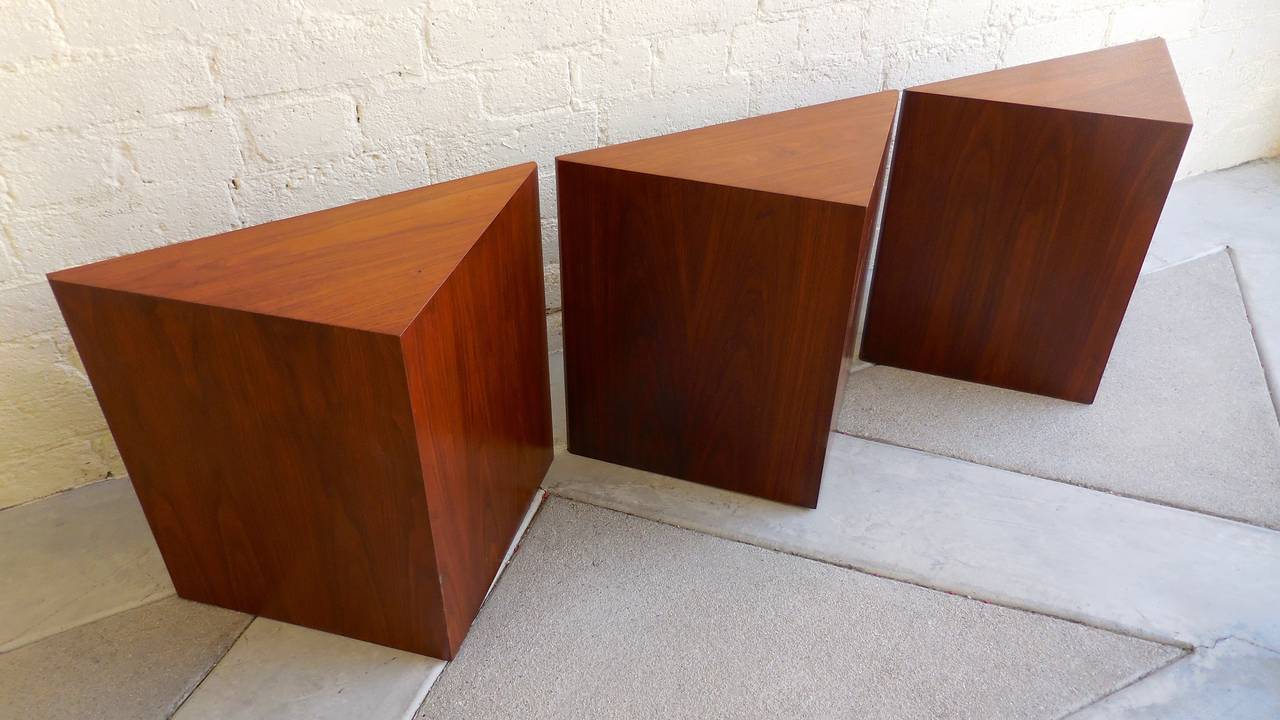 An interestingly geometric set of three walnut veneered triangular occasional tables from the 1960's.  Each of the tables is finished on the top and all sides in gorgeous figured walnut veneer.  They have been professionally cleaned an polished and