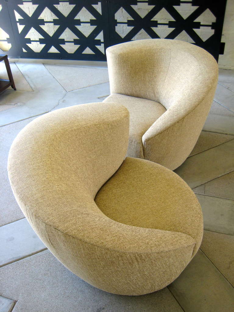 A pair of swiveling circular Corkscrew chairs, designed by Vladimir Kagan for Directional Furniture in 1992.  The pair of chairs are a true left and right and are newly reupholstered in a beige woven fabric.  These are the perfect fireside or