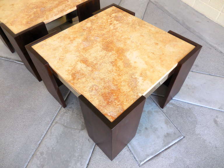 A beautifully tailored pair of 1960's Brazilian mahogany and brass side side tables. This handsome pair has new golden travertine tops. The brass trim right under the slab top and visible along the sides connects the four corner leg constructs.