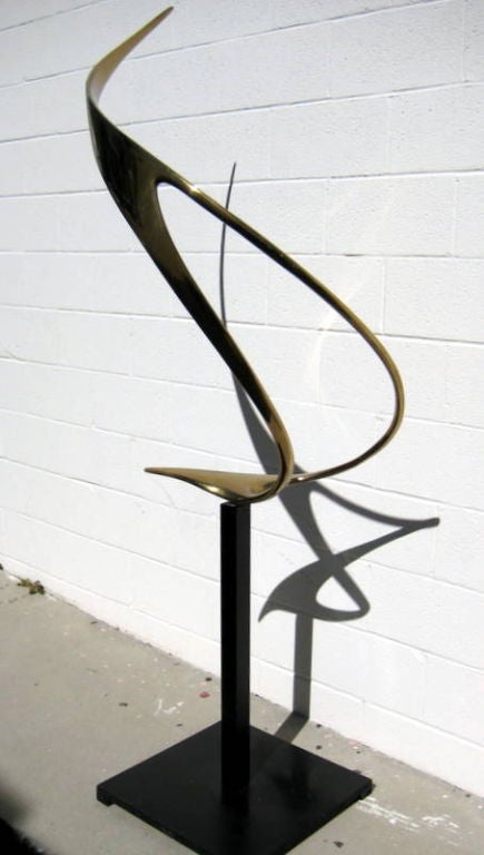 A polished bronze sculpture fabricated in 1982 by famed Bay Area sculptors Lou Pearson and Robbie Robbins. The custom pedestal into which the sculpture is slotted has ball bearings in the mounting slot that allow the sculpture to rotate easily with