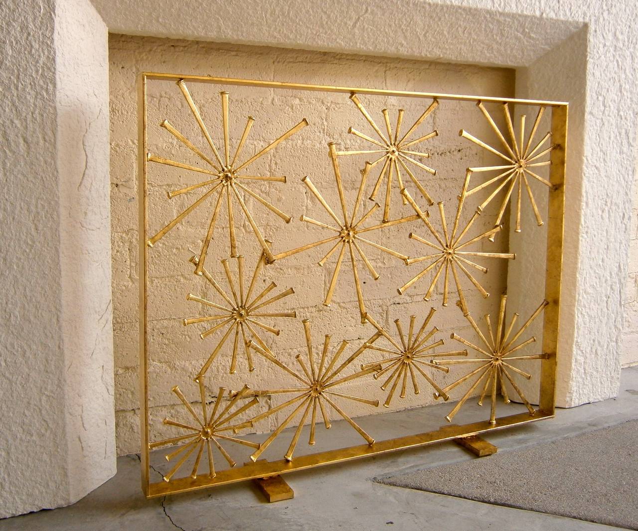 A gilded steel asymmetrically designed starburst fire screen by American artist Del Williams.  The screen was custom crafted in Mr. Williams' Southern California studio using steel pieces that have been hand-welded and hand-gilded.  This screen is