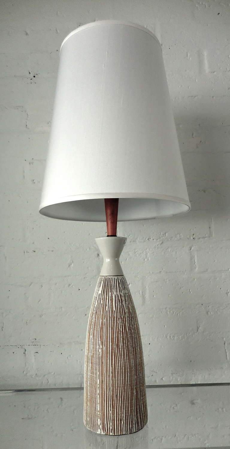A finely made Danish porcelain table lamp with a teak wood neck from the 1960s.  This lamp has been newly rewired and includes the shade.  The dimensions of the base alone is 14.5