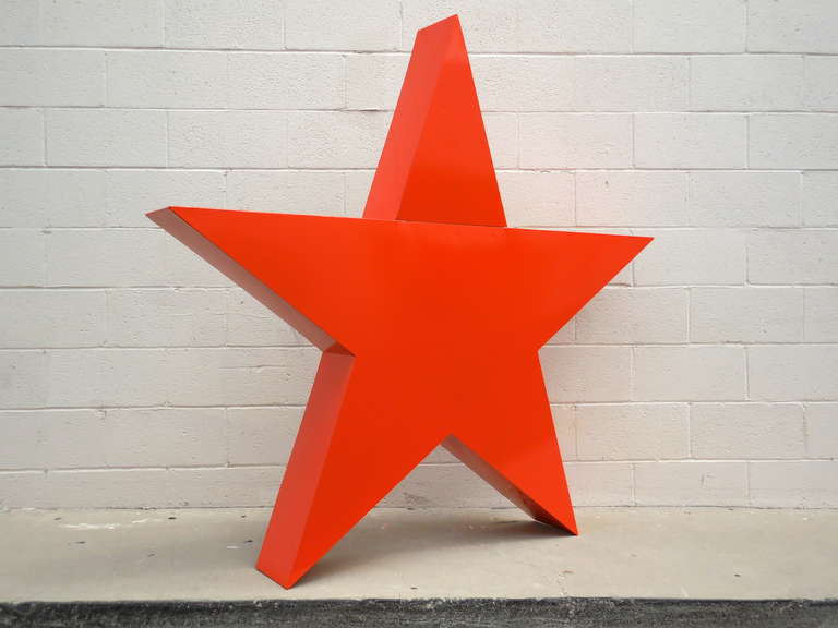 Your very own giant powder coated steel three-dimensional star.  Originally a trade sign from the 1970s, the star can hang on a wall or stand freely.  It has been newly powder coated in a vibrant orange color.  The top point is 