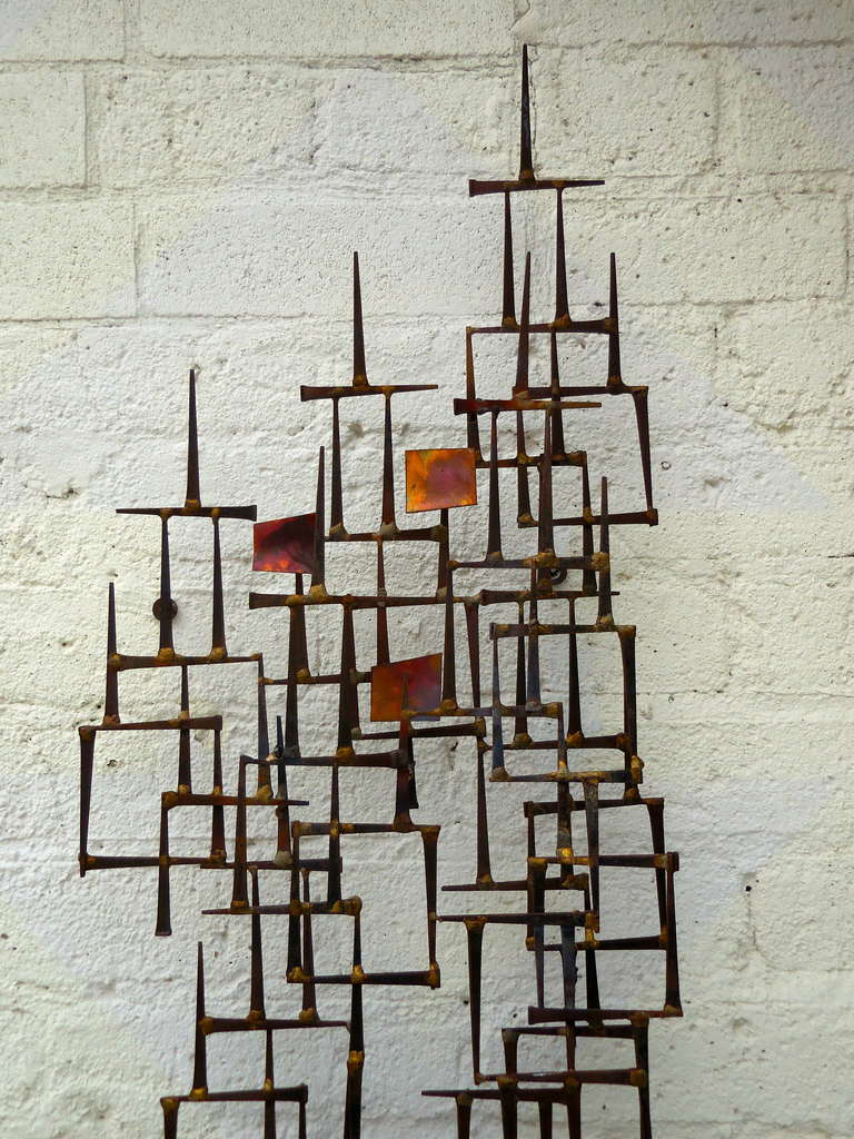 An unsigned asymmetrical Brutalist steel and copper wall sculpture from the 1960s.  This piece is in the manner of American studio artist William Bowie. Rusticated square steel nails have been brazed together with flat pieces of copper to create a