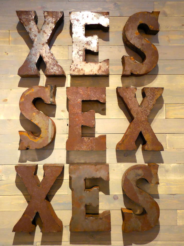 Composed of hand welded and weather patinated channel letters, this cheeky stack of letters is at once provocative, humorous, compelling and sarcastic. The back of each individual letter is drilled and prepared for hanging and the letters can be