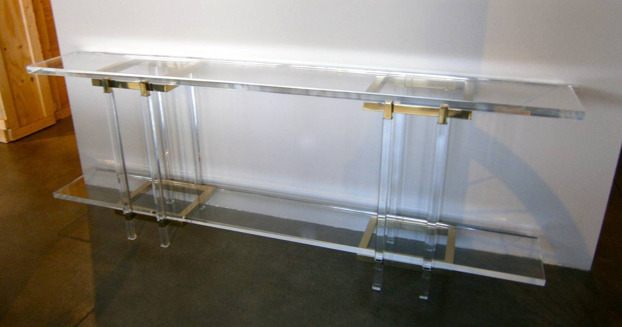 A two-tier acrylic and brass-plated steel console table from the Metric Line designed by the Lucite legend Charles Hollis Jones. This shallow console table has planks of acrylic that are suspended between a pair of acrylic and brass-plated towers.