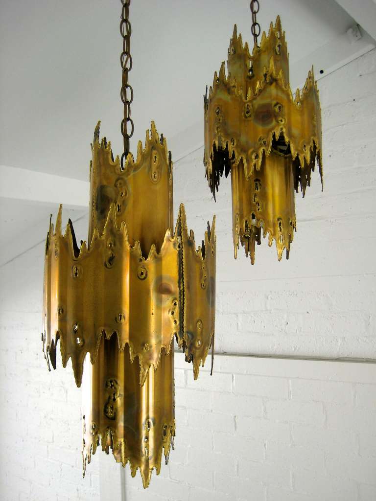 A pair of pierced, torch cut and patinated brass Brutalist pendant lights designed by Tom Greene for either Monteverdi Young or Feldman Lighting Co. of Los Angeles.  C.1960's.