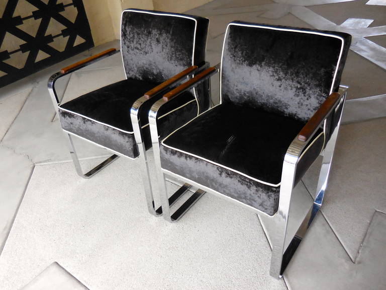 A pair of beautifully proportioned chrome-plated steel armchairs with mahogany armrests circa 1970s. The design of the chairs is attributed to Milo Baughman for Design Institute America. The pair of chairs retains its original plating and have been