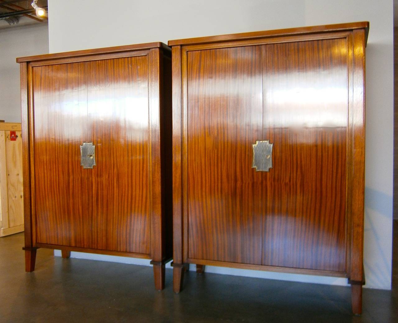 A fantastic pair of French Art Moderne cabinets with gilt metal escutcheons attributed to Gilbert Poillerat  C.1940s. The cabinets were made from choice "ribbon" mahogany and the interiors are veneered in sycamore.  One cabinet has
