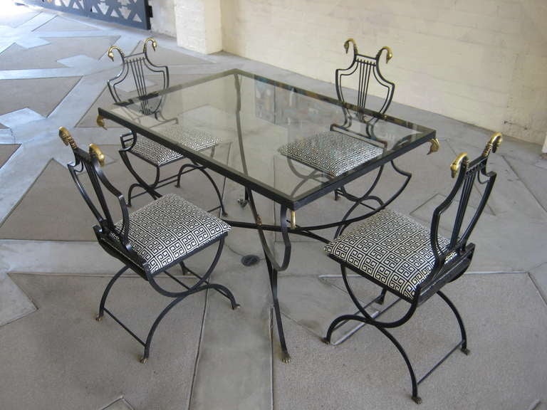 A chic and glamorous Italian iron lyre-back patio set with bronze foot and swan head details.  The set comprises a hard-to-find rectangular glass-topped dining table and 4 chairs that fold up for off-season storage.  The chairs have been newly