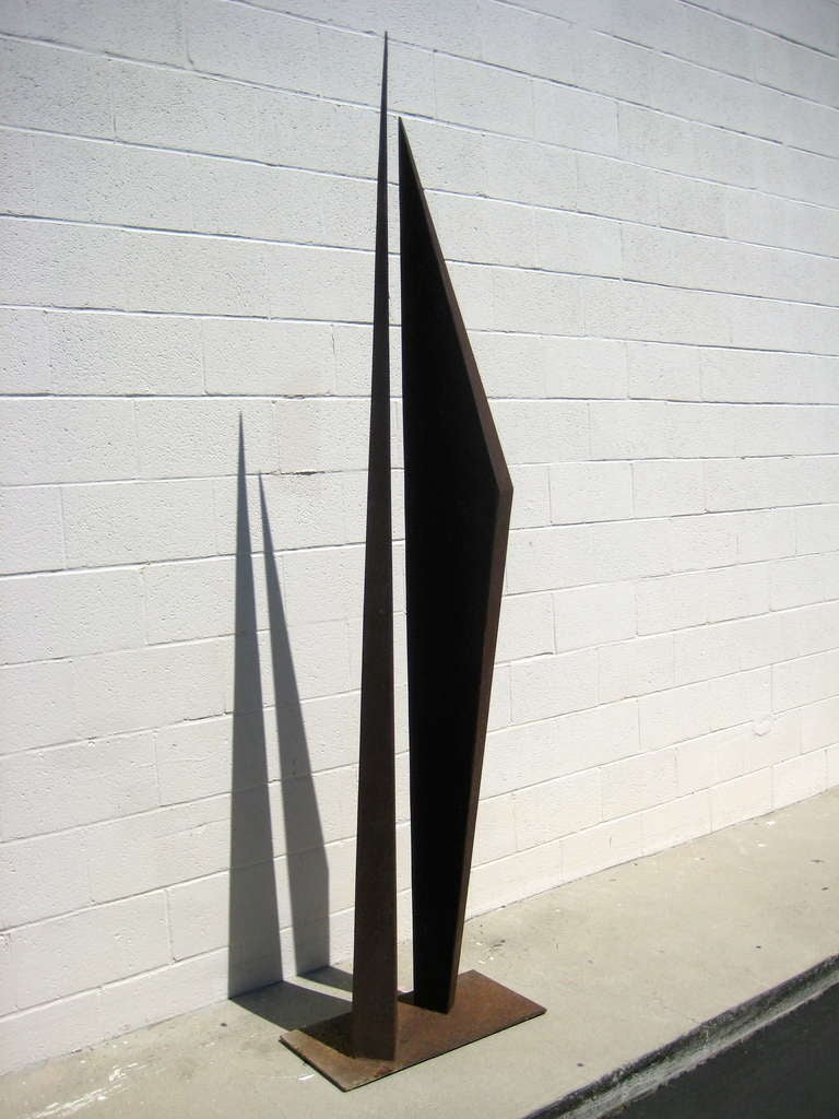A steel outdoor sculpture by Los Angeles artist James Hill.  The steel has an oxidized and weather finish.  The two upright pieces can be viewed as figures with a tension and dynamic in play.  The shadows cast by the 
