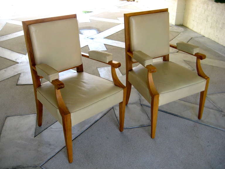 A chic and stylish pair of French sycamore framed armchairs with leather upholstery in the style of Andre Arbus. The chairs have neoclassical styling that would integrate well in either a modern or a traditional interior. The leather is a neutral,