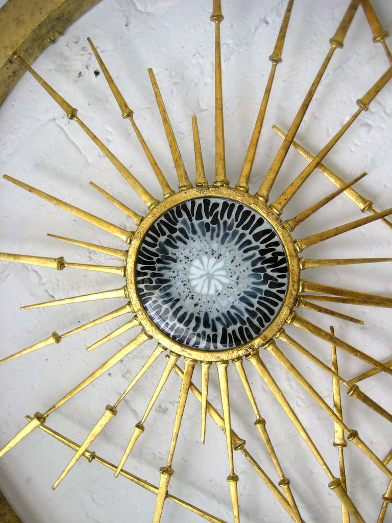 One of a series of rondo wall sculptures produced by California artist Del Williams. Hand made glass and steel star bursts are layered and incorporated into a circular metal frame in an asymmetrical pattern. The entire sculpture has been gold leafed