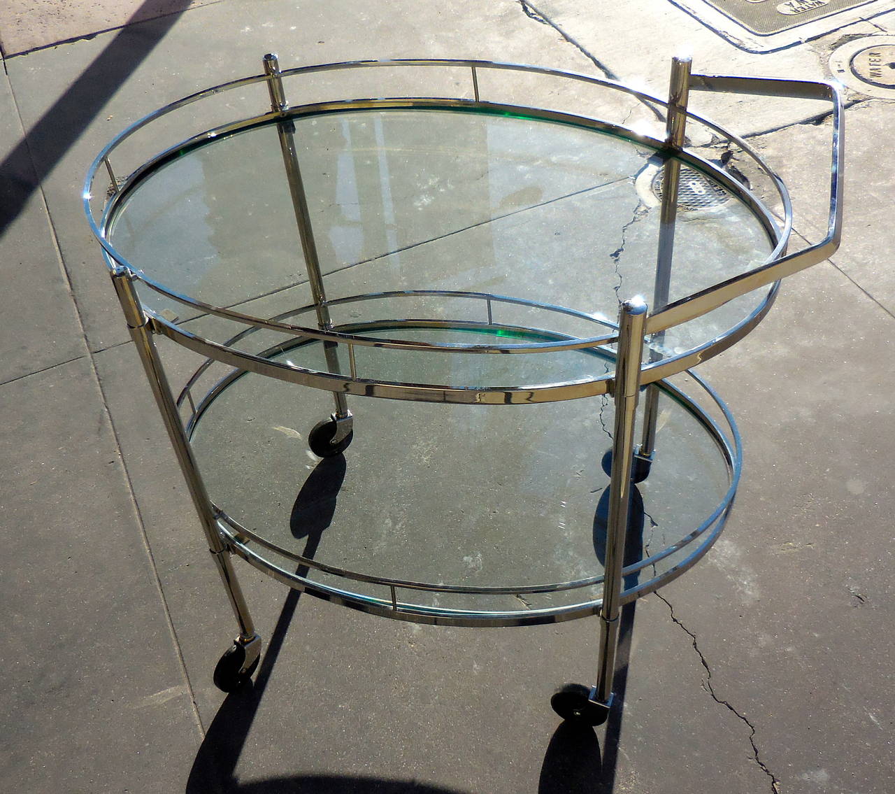 A nickel-plated oval two-tier serving or bar cart, attributed to the New York City firm of Maxwell-Phillips in the 1950s. The cart has recently been nickel-plated over solid brass and the glass shelves are new replacements. The handle is removable