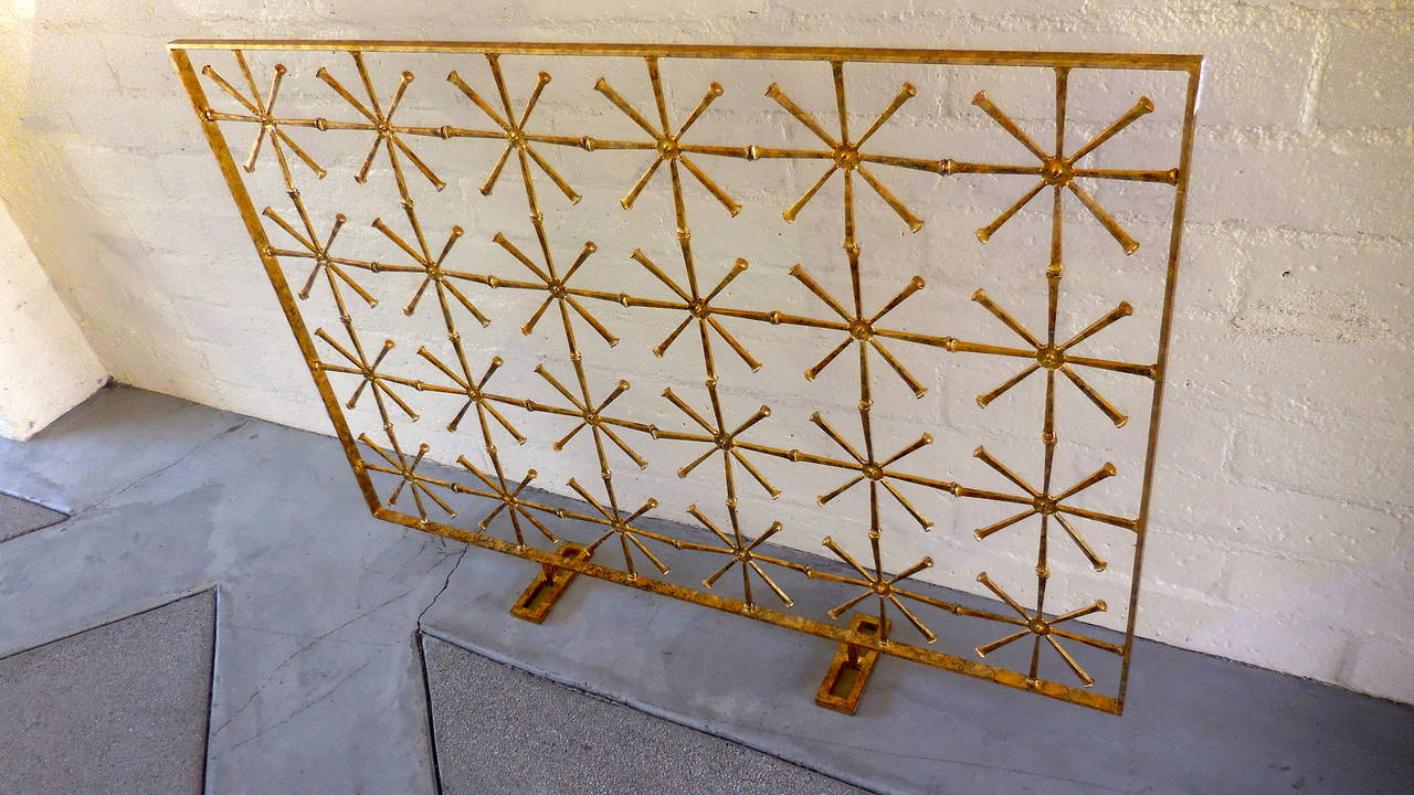 A glittering hand gold leafed fire screen with a modernist motif of 24 stars set into an outer gold leafed frame. Del Williams sculpted this screen in 2013 using traditional welding techniques.