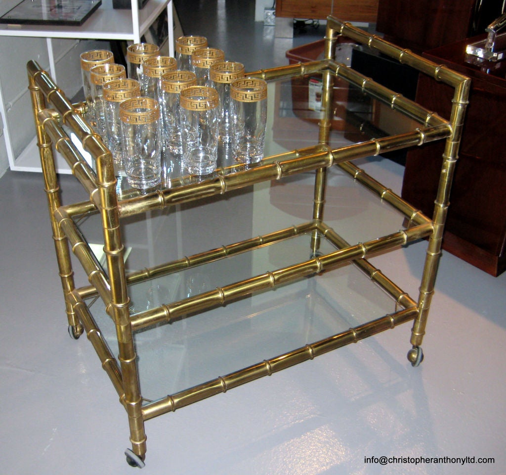 A large, very well proportioned Italian bar cart with a striking bamboo design rendered in brass. This ample cart has three brand new glass shelves and rolls confidently on four vintage 