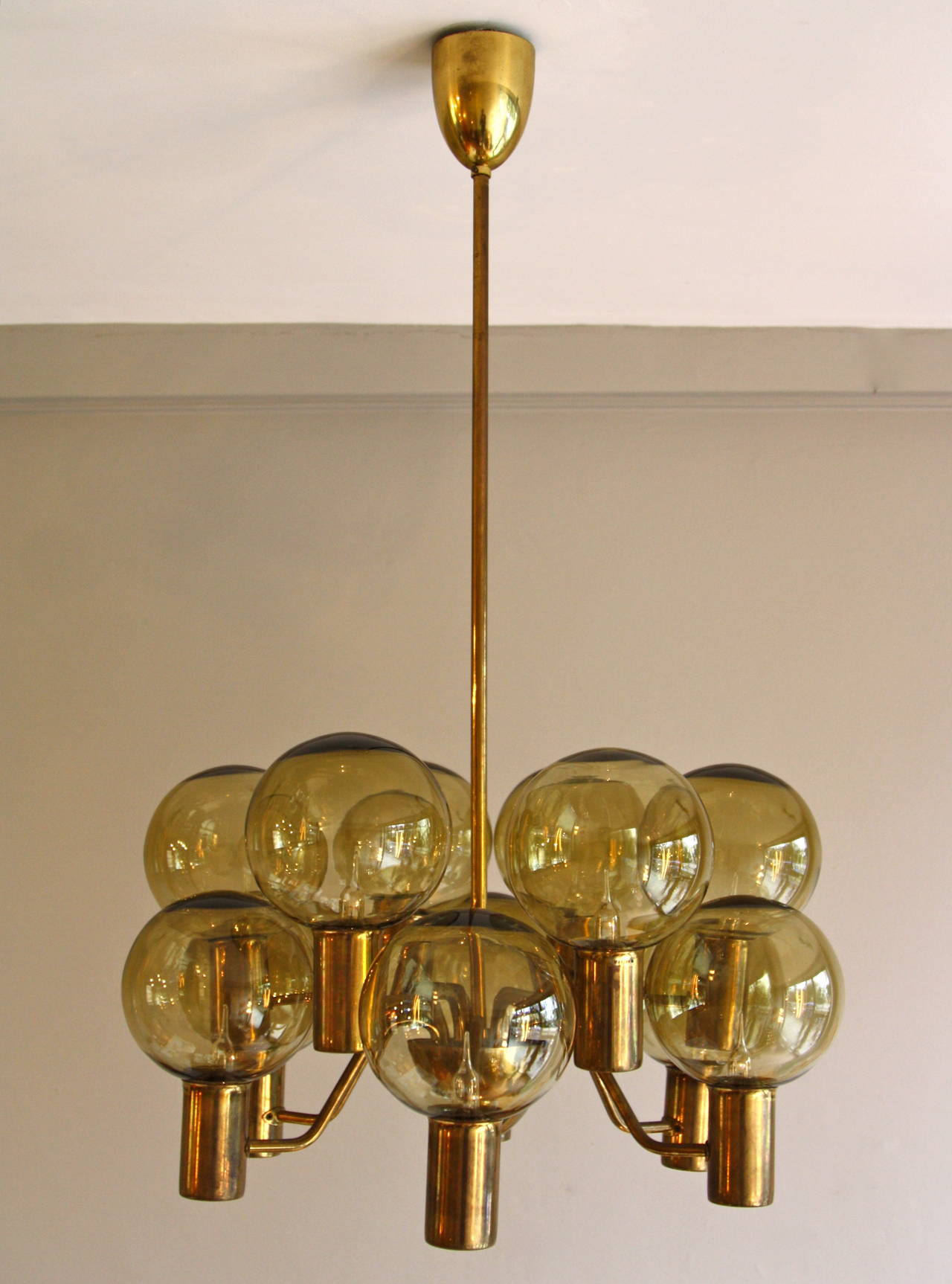 Beautiful twelve armed chandelier in brass with smoked glass globes.