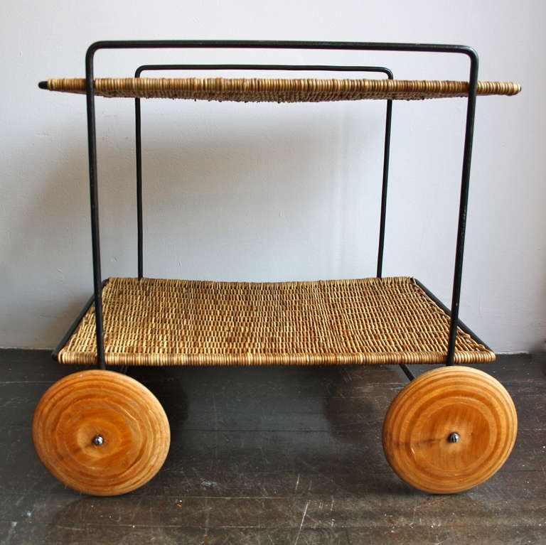 Beautifully proportioned trolley by Carl Auböck. Black painted metal frame , wicker shelves and plywood wheels , - all is was intended to be.