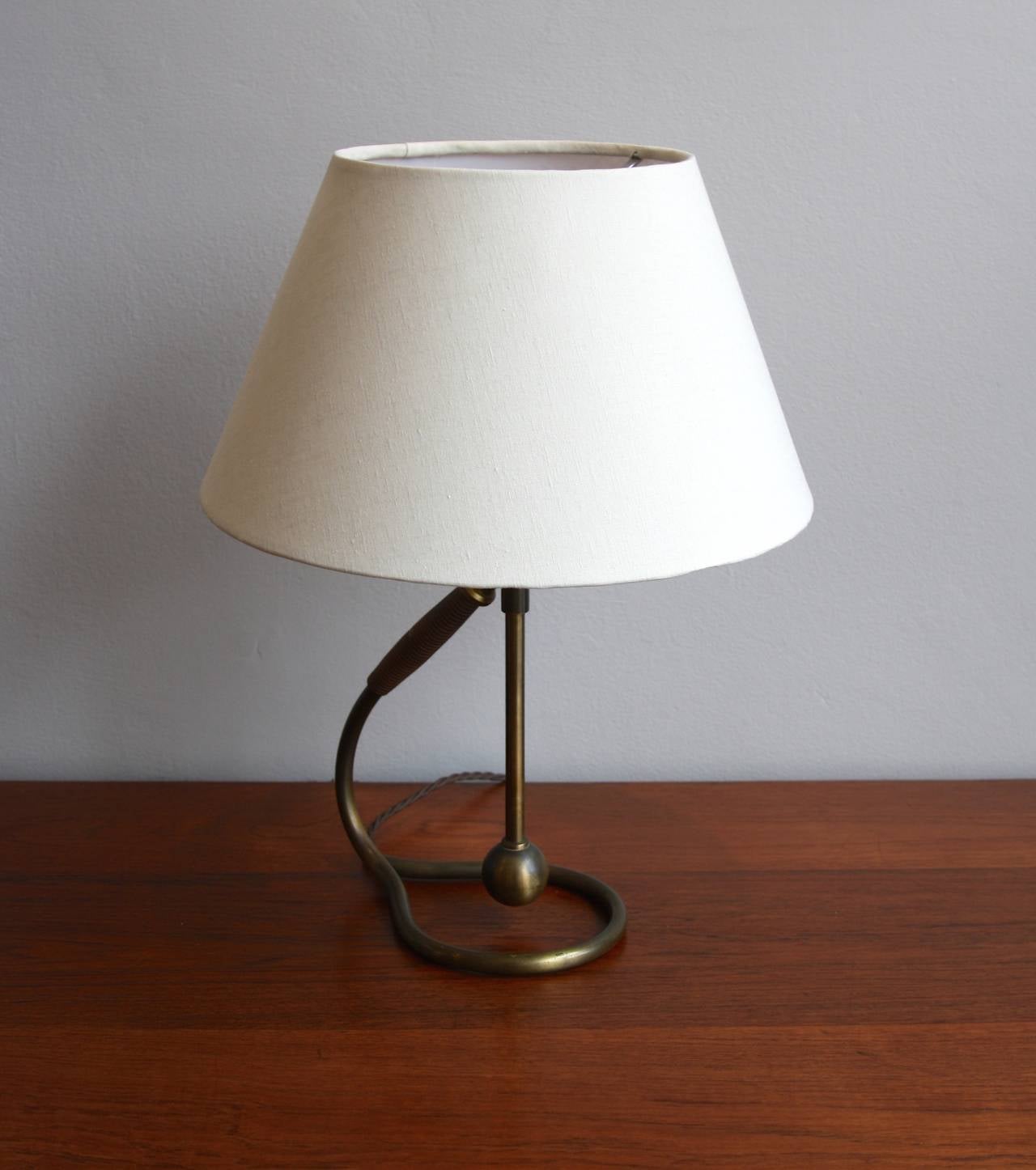 Graceful table or wall lamp made by Kaare Klint, Denmark, 1940s. Brass stem with bakelite handle. Adjustable, it can stand on a flat surface or be hung on a wall.